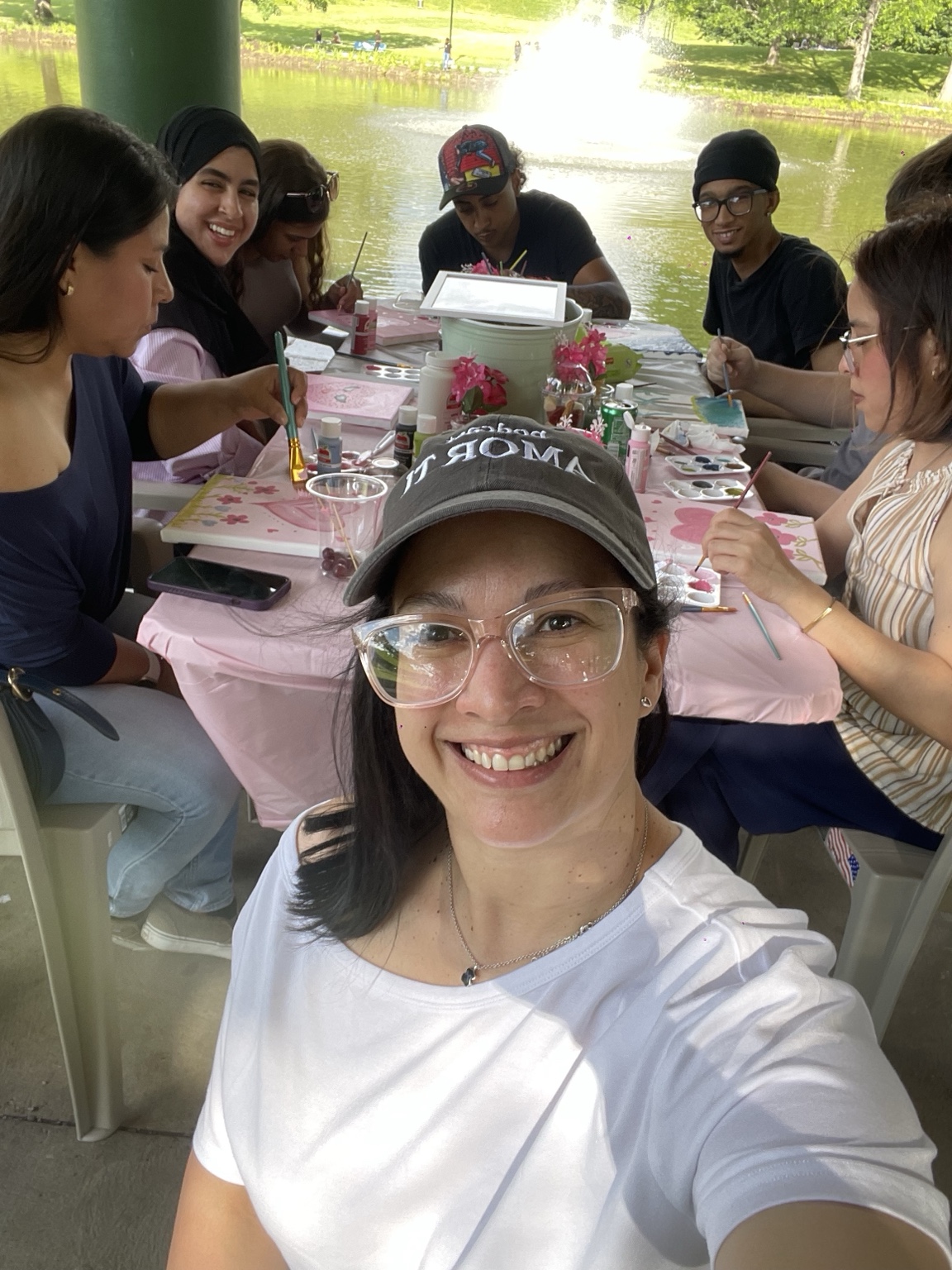 Yohanna sonríe junto a participantes mientras pintan